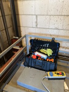 B&W International toolbox filled with tools, spray cans and a rag, ready for use on a construction site.